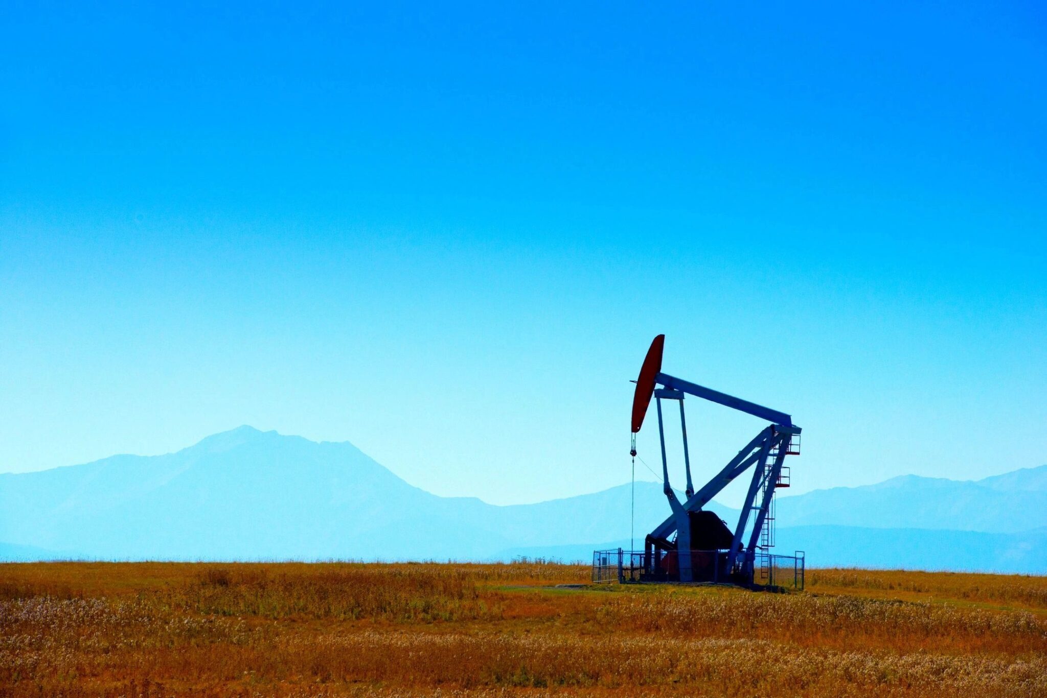 A pump jack in the middle of an open field.